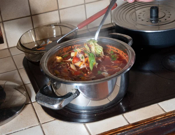 Çorbayı tavada yoğuran kadın, adım adım çorbayı pişiriyor.