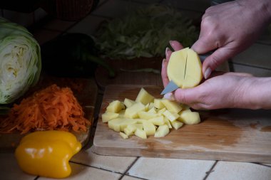 Bir kadın mutfakta taze sebzelerin arka planında patates kesiyor. Aşama aşama çorba yapmak için gerekli malzemeler. Yüksek kalite fotoğraf
