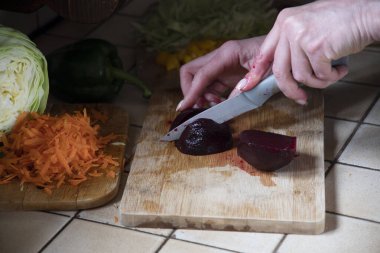 Bir kadın mutfakta taze sebzelerin arka planına pancar kesiyor. Aşama aşama çorba yapmak için gerekli malzemeler. Yüksek kalite fotoğraf