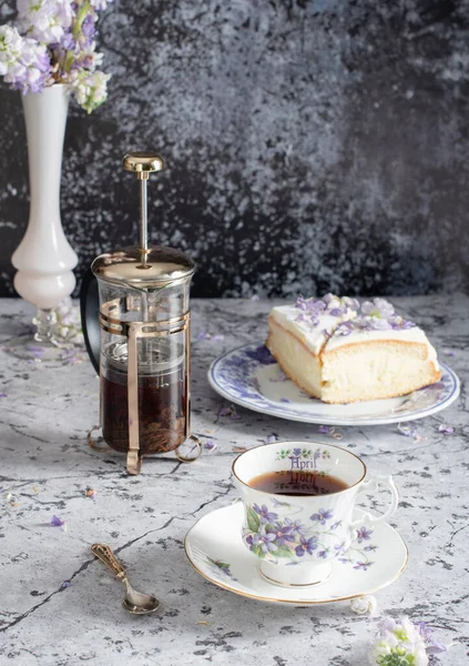 Still life with black tea and cheese cake, spring bouquet,delicate lilac flowers — Stock Photo, Image