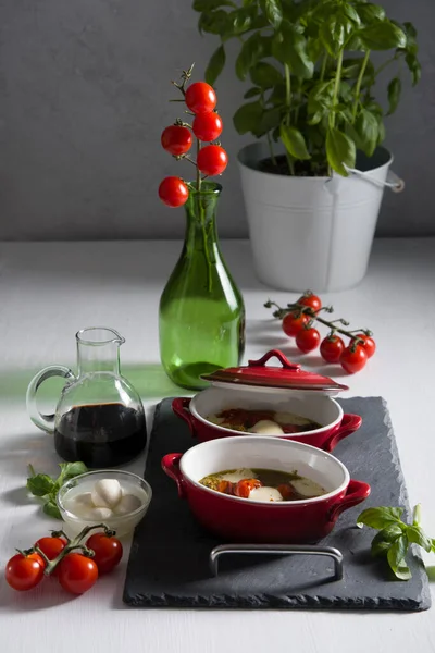 Italian caprese salad, baked cherry tomatoes, mozzarella and basil on a table — Stock Photo, Image