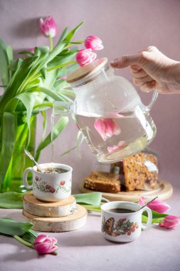 Hayat, erken bahar kahvaltısı konsepti kahve, çay ve bir buket lale ve nergis çiçeğinin arka planında kek.
