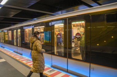 Brüksel, Belçika - 01.31.2021 Maskeli insanlar orada otururken büyük bir şehirde genç bir kadın metro vagonuna biniyor. Yüksek kalite fotoğraf