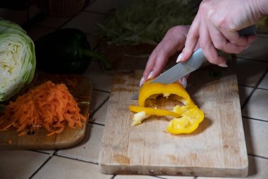 Masada sarı dolmalık biber kesen bir kadın mutfakta taze sebzelerin arka planına pancar kesiyor. Aşama aşama çorba yapmak için gerekli malzemeler. Yüksek kalite fotoğraf