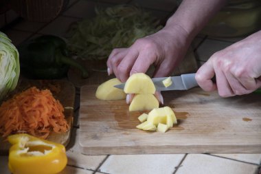 Bir kadın mutfakta taze sebzelerin arka planında patates kesiyor. Aşama aşama çorba yapmak için gerekli malzemeler. Yüksek kalite fotoğraf
