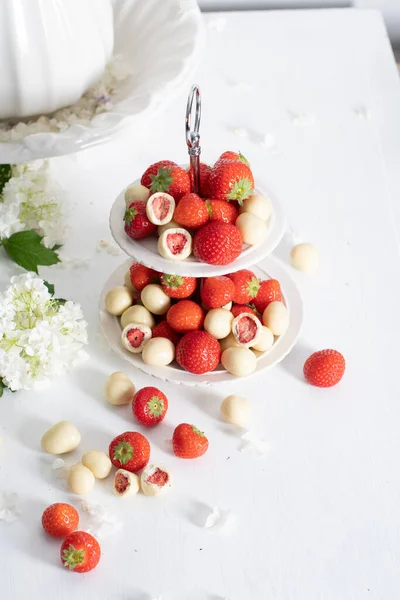 vase with white chocolate covered strawberries and fresh strawberries against porcelain vase with hydrangea, vintage still life and summer food. High quality photo