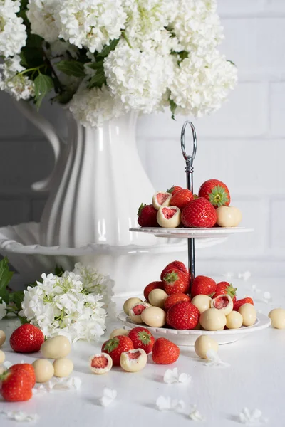 vase with white chocolate covered strawberries and fresh strawberries against porcelain vase with hydrangea, vintage still life and summer food. High quality photo