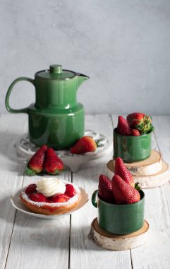 Meyveli, çilekli ve yeşil çay takımlı bir hayat kremalı çilekli pasta, bir kadın eli tatlı çatalıyla bir dilim pastayı kırar. Yüksek kalite fotoğraf