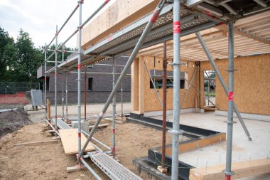 strong metal scaffolding at the construction site of a new house, the beginning of wooden structures around a metal frame. High quality photo