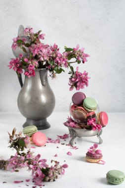 rengarenk badem kurabiyeleri ve pembe elma ağacı çiçekleriyle dolu bir vazo, renkli tatlı yiyecekler. Yüksek kalite fotoğraf