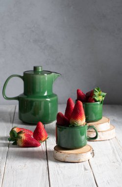 Meyveli, çilekli ve yeşil çay takımlı bir hayat kremalı çilekli pasta, bir kadın eli tatlı çatalıyla bir dilim pastayı kırar. Yüksek kalite fotoğraf