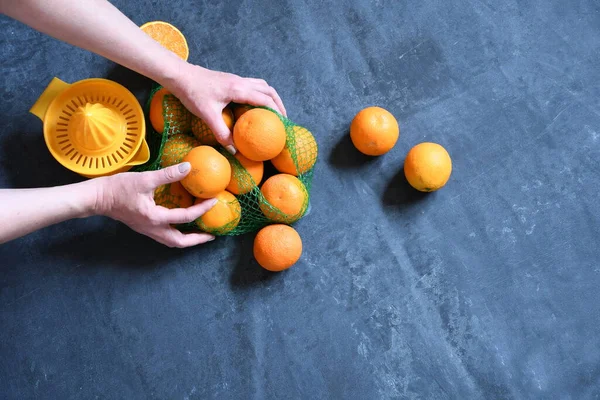 female hands make juice from oranges using a manual juicer, Orange on a blue background, summer dessert on a hot day, vitamin color drink, flatlay oranges. High quality photo