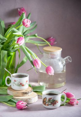 Hayat, erken bahar kahvaltısı konsepti kahve, çay ve bir buket lale ve nergis çiçeğinin arka planında kek.