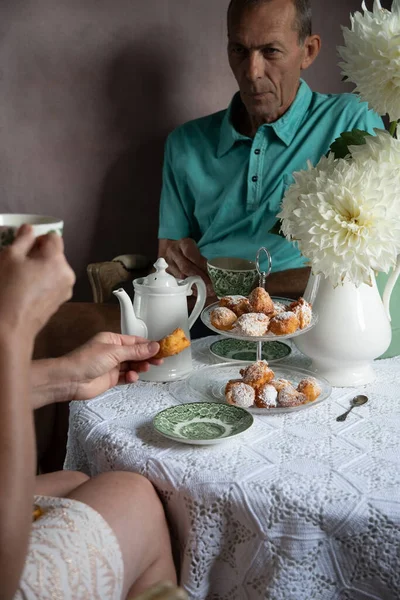 tea break in the English style, still life with flowers and donuts in the morning sun, homemade cakes, married couple drinking tea together at breakfast in english style, beautifully set table