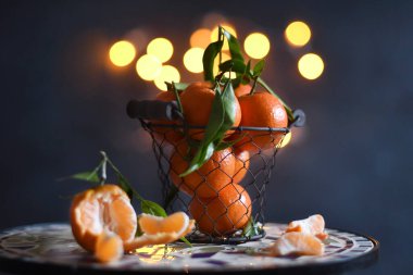 tangerines in a mesh bucket on a table against a background of bright yellow bokeh, New Years mood. High quality photo