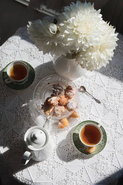 English style tea break, still life with flowers and donuts in the morning sun, homemade cakes, food from above. High quality photo