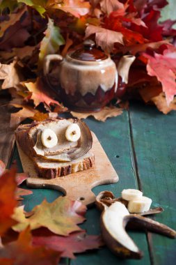 Parlak sonbahar yaprakları, bakır kahve öğütücüsü ve ahşap zemin üzerinde kahve olan seramik fincanda gözleri olan yaratıcı muzlu kek hayatı. Yüksek kalite fotoğraf