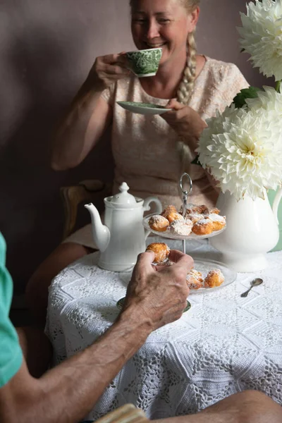 tea break in the English style, still life with flowers and donuts in the morning sun, homemade cakes, married couple drinking tea together at breakfast in english style, beautifully set table