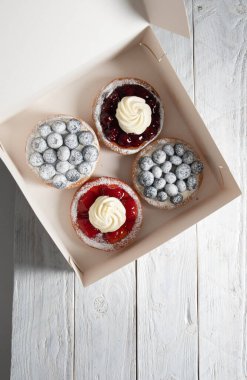 Kutuda farklı hamur işleri, böğürtlenli taze pastalar, krem şanti, tatlı eve servis. Yüksek kalite fotoğraf