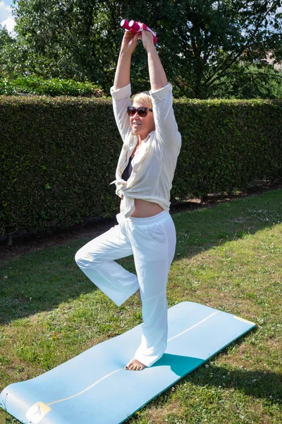 middle aged caucasian doing yoga in the garden in summer sporty lifestyle at any age. High quality photo