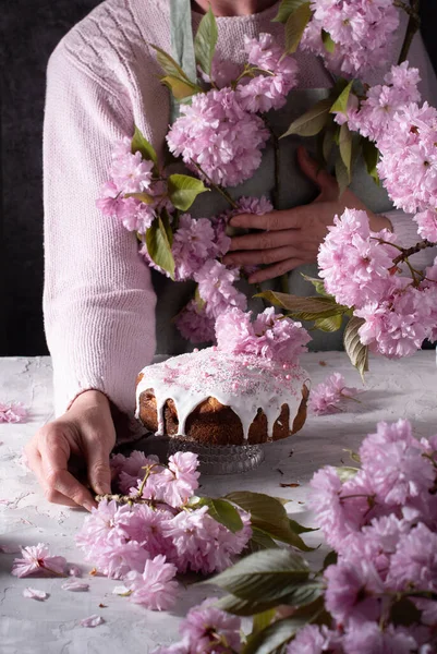 ピンクの桜の花 春の花 テーブルの上のピンクの桜の花の花束 装飾された春の部屋 美しい静物画で手作りのイースターケーキを飾る女性 高品質の写真 — ストック写真
