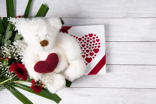 Valentines day gift, teddy bear with a heart, a box of pralines and a bouquet of flowers on the bed early in the morning. High quality photo