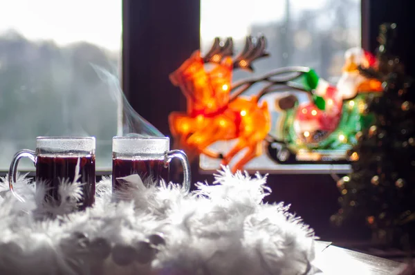 hot steaming mulled wine in mugs against the background of decorated Christmas tree. High quality photo
