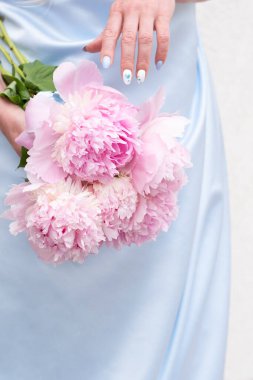 Bir buket pembe şakayık desenli mavi gelinlik içinde gelin, pastel cennet çiçekli arka plan, tamamlayıcı renk kombinasyonu. Yüksek kalite fotoğraf