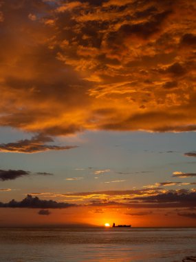 Sahilde güzel bir gün batımı turuncu ve mavi gökyüzü, okyanus dalgaları ve uzakta bir tekne. Pedernales Dominik Cumhuriyeti