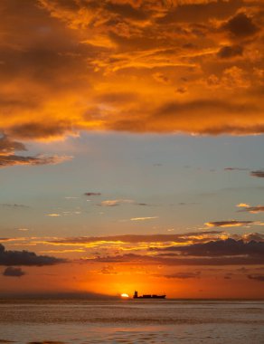 Sahilde güzel bir gün batımı turuncu ve mavi gökyüzü, okyanus dalgaları ve uzakta bir tekne. Pedernales Dominik Cumhuriyeti
