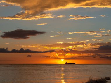 Sahilde güzel bir gün batımı turuncu ve mavi gökyüzü, okyanus dalgaları ve uzakta bir tekne. Pedernales Dominik Cumhuriyeti