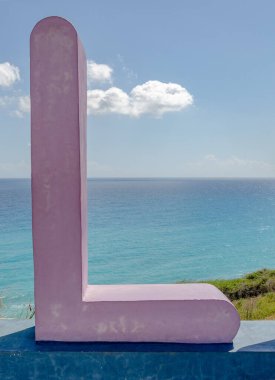 Mor, arkasında Karayip Denizi olan L harfinin beton heykeli..