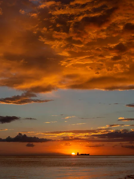 Sahilde güzel bir gün batımı turuncu ve mavi gökyüzü, okyanus dalgaları ve uzakta bir tekne. Pedernales Dominik Cumhuriyeti