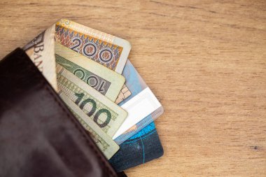 Bir sürü Polonyalı banknot ve kredi kartları kahverengi deri bir cüzdana yapışmış. Fotoğraf yapay, yumuşak ışık altında çekildi