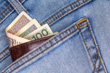 Cüzdan ve kot pantolonun arka cebinden çıkan bir sürü Polonya banknotları. Fotoğraf yapay, yumuşak ışık altında çekildi