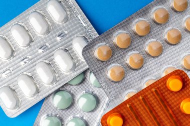 Su toplamış haplar mavi arka planda sunuluyor. Fotoğraf yapay ışık altında çekildi