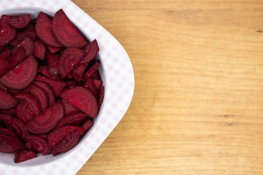 Plastik bir kaseye yerleştirilmiş taze pancar parçaları. Fotoğraf yapay, yumuşak ışık altında çekildi.