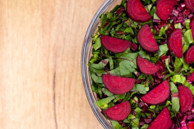 Taze, kesilmiş yapraklar ve cam bir kaseye yerleştirilmiş pancar parçaları. Fotoğraf yapay, yumuşak ışık altında çekildi.