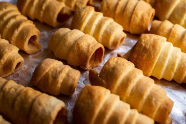 Bir sürü ev yapımı şekerleme tüpü kremayla doldurulmaya hazır. Fotoğraf yumuşak yapay ışık altında çekildi.