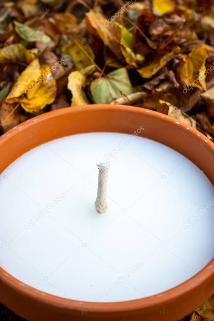 Top view of the graveyard candle on background of a golden autumn leaves. Photo taken in soft daylight