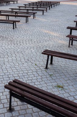 Bir meydanda granitle döşenmiş bir sürü bank var. Fotoğraf doğal ışık altında çekildi. Hafif gölgeli bir yer.