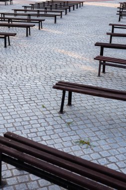 Bir meydanda granitle döşenmiş bir sürü bank var. Fotoğraf doğal ışık altında çekildi. Hafif gölgeli bir yer.
