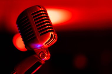 Klasik sahne mikrofonu. Renkli ışıkla aydınlatılmış nesne. Arka planda, sahnedeki bulanık ışık manzarası.