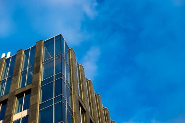 Mavi gökyüzü arka planına karşı modern bir apartmanın cephesi. Fotoğraf, güneşli bir günde öğleden sonra çekildi..