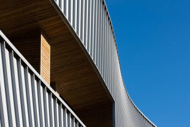 Mavi gökyüzü arka planına karşı modern bir kamu binasının cephesi. Fotoğraf, güneşli bir günde öğle vakti çekildi..