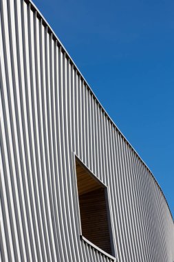 Mavi gökyüzü arka planına karşı modern bir kamu binasının cephesi. Fotoğraf, güneşli bir günde öğle vakti çekildi..