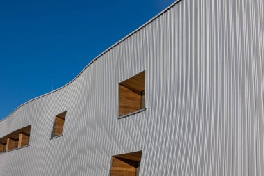 Mavi gökyüzü arka planına karşı modern bir kamu binasının cephesi. Fotoğraf, güneşli bir günde öğle vakti çekildi..