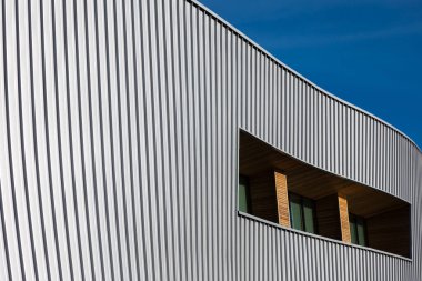 Mavi gökyüzü arka planına karşı modern bir kamu binasının cephesi. Fotoğraf, güneşli bir günde öğle vakti çekildi..