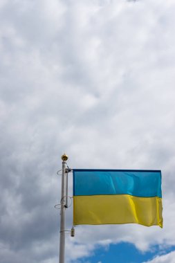 Bulutlu, dramatik gökyüzünün arka planında Ukrayna bayrağı dalgası. Resim gündüz çekildi, gökyüzü bulutlarla dolu..  