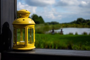 Bahçe terasının korkuluğunda sarı bahçe feneri. Fotoğraf, güneşli bir günde, iyi ışıklandırma koşullarıyla çekildi..